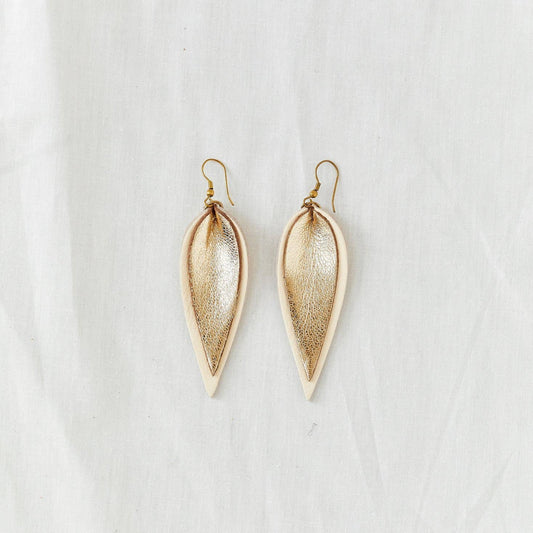 Pair of two-tone cream and metallic gold leather earrings in the shape of an upside-down teardrop in front of a white backdrop